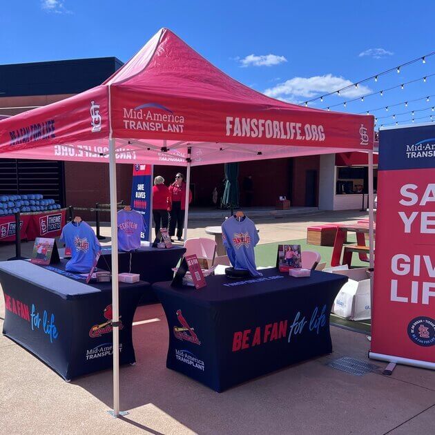 Fans For Life booth at Busch Stadium. A red banner on the side reads "Say Yes Give Life"