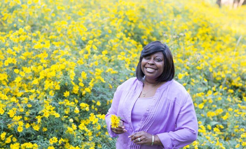 Nikki stands in a field of yellow flowers