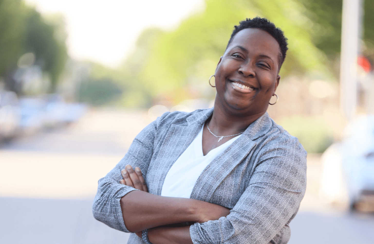 Dr. Brittany Clayborne stands with arms crossed, smiling. She is wearing a grey plaid blazer.